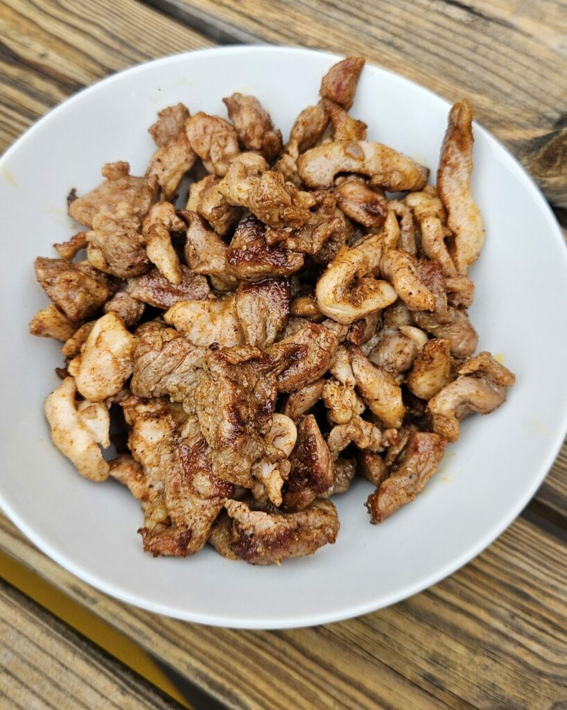 Poulet shawarma mariné aux épices et grillé, servi en morceaux dans un bol blanc.