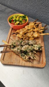 Brochettes de poulet Chich Taouk et brochettes d’agneau marinées aux herbes, servies sur planche avec salade fraîche.