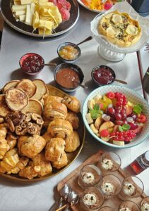 Buffet brunch composé de quiche, saumon fumé, fromages et charcuterie, viennoiseries, confitures maison, salade de fruits et verrines dessert.
