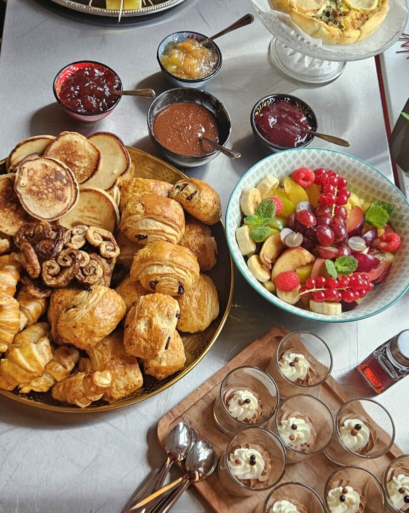 Buffet brunch composé de quiche, saumon fumé, fromages et charcuterie, viennoiseries, confitures maison, salade de fruits et verrines dessert.