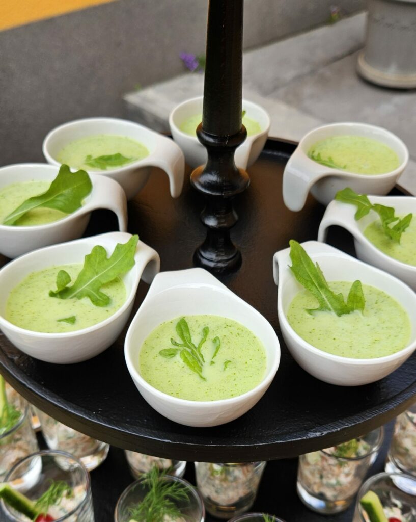 Verrines de potage de concombre frais, décorées de roquette, servies en mini-bols pour cocktail ou buffet.