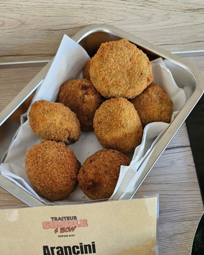 Barquette en inox remplie d’arancini dorés aux épinards, croustillants et prêts à déguster.
