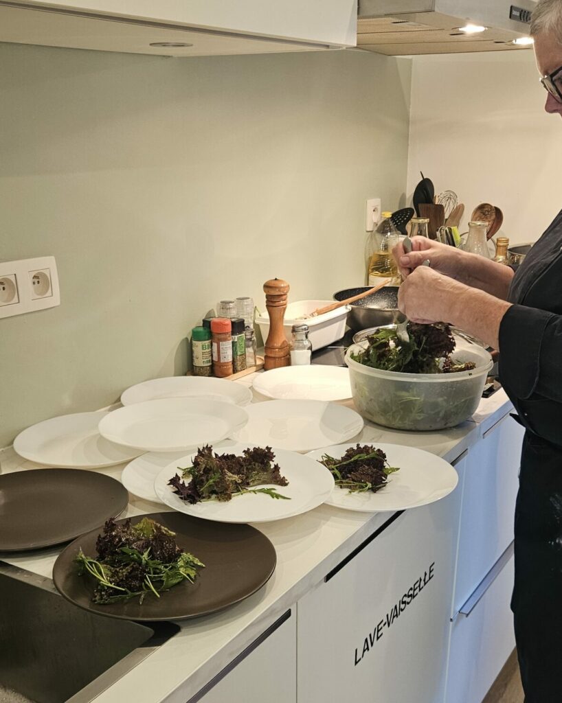 Chef préparant des assiettes de salade verte en cuisine professionnelle