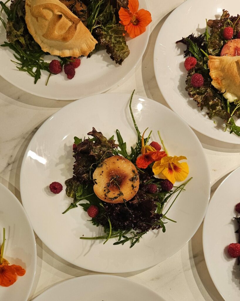 Assiette de salade gourmande avec poire rôtie, fleurs comestibles et framboises fraîches