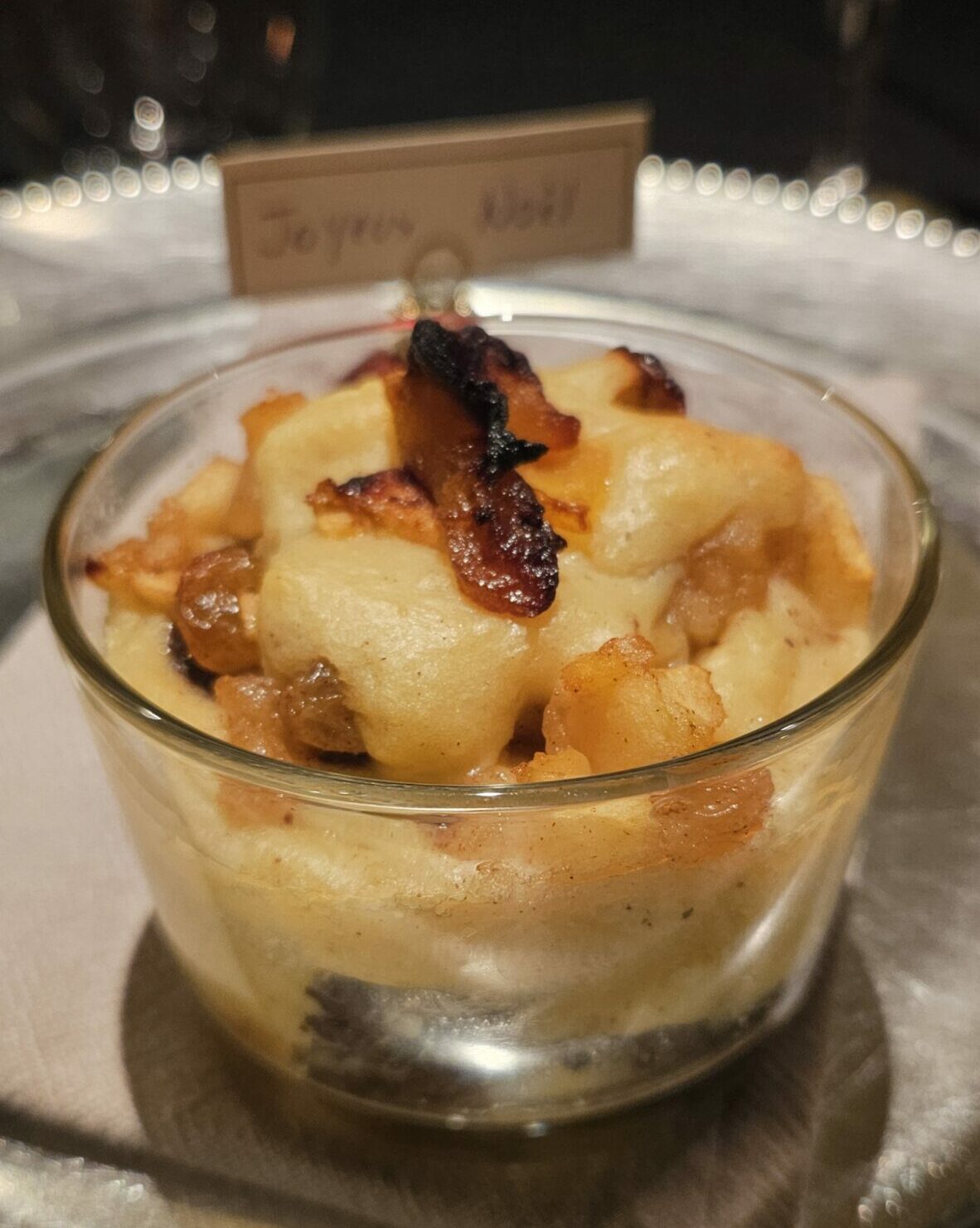 Verrine de tiramisu salé au boudin noir et pommes caramélisées, servie chaude dans un ramequin en verre sur une table de fête.