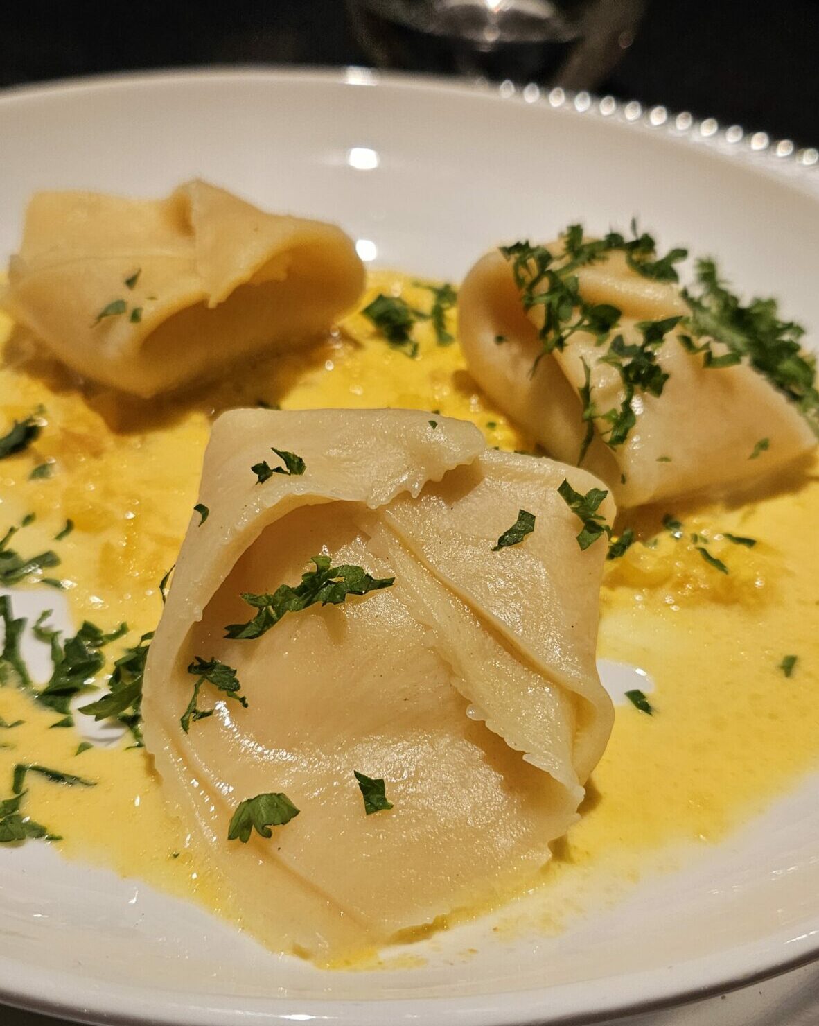 Assiette de tortellinis à la ricotta, nappés d’une sauce crémeuse au citron et parsemés de persil frais.