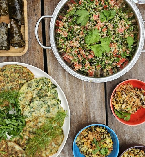 Assortiment de mezzés libanais comprenant taboulé, houmous, feuilles de vigne farcies, omelettes aux herbes et riz aux lentilles.